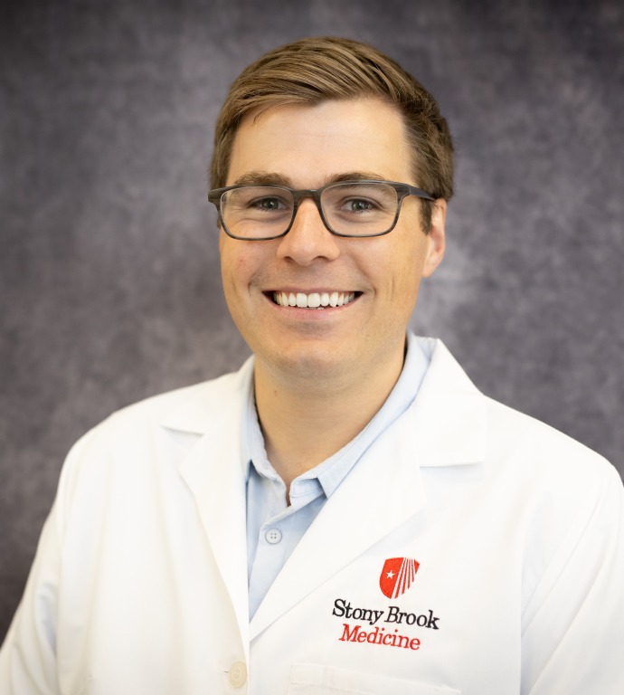 quinn Kensey Resident in a Doctor's white coat with a gray background